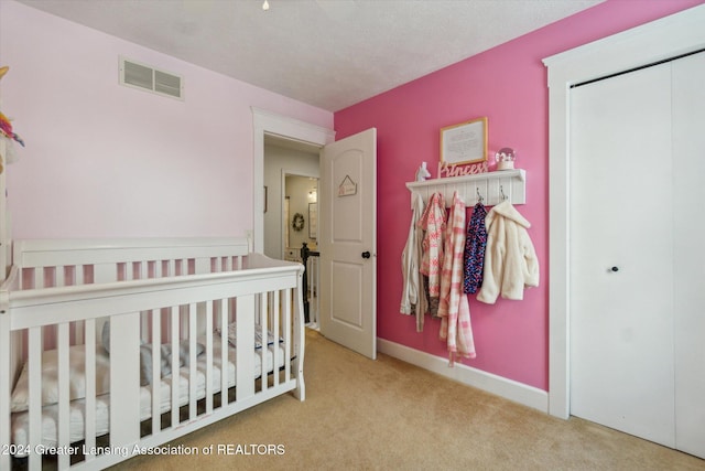 carpeted bedroom with a textured ceiling, a closet, and a nursery area