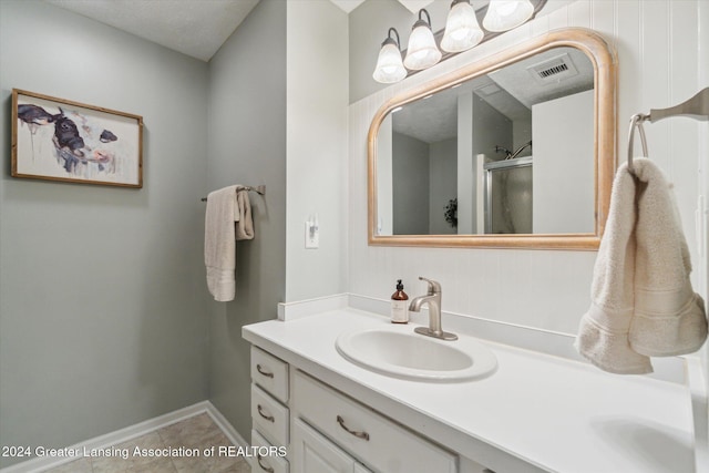 bathroom with tile patterned floors, walk in shower, and vanity