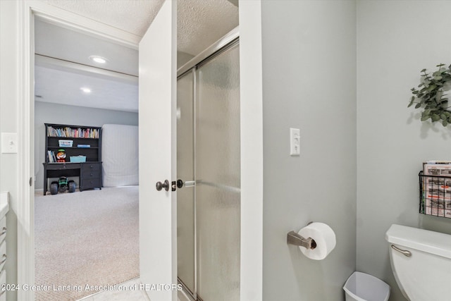 bathroom featuring a textured ceiling, toilet, and a shower with door