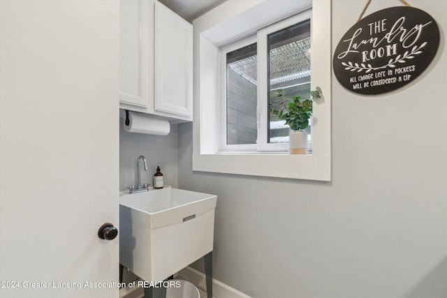 laundry area with cabinets and sink