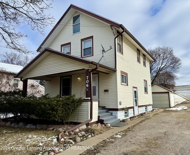 front of property featuring covered porch, a garage, and an outdoor structure