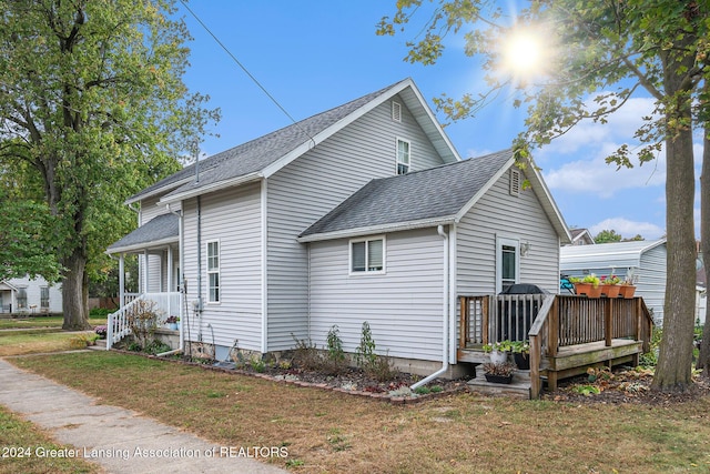 view of side of home with a deck and a lawn