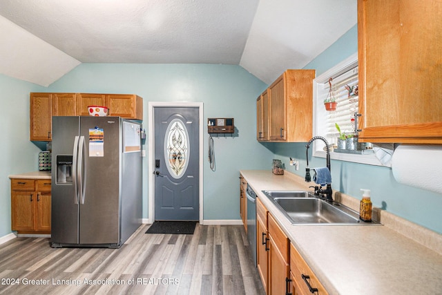 kitchen with appliances with stainless steel finishes, a textured ceiling, sink, wood-type flooring, and lofted ceiling