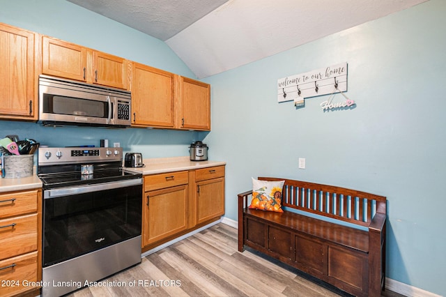 kitchen featuring a textured ceiling, stainless steel appliances, lofted ceiling, and light wood-type flooring