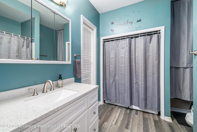 bathroom with a shower with shower curtain, vanity, wood-type flooring, and toilet