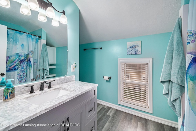 bathroom featuring a textured ceiling, vanity, hardwood / wood-style flooring, and lofted ceiling