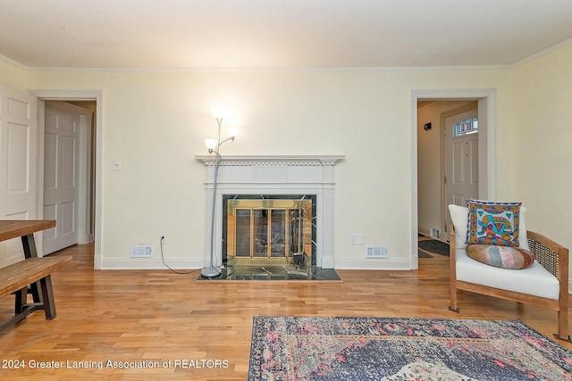 living room with crown molding, light hardwood / wood-style floors, and a tile fireplace