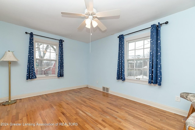 spare room with ceiling fan, a healthy amount of sunlight, and wood-type flooring