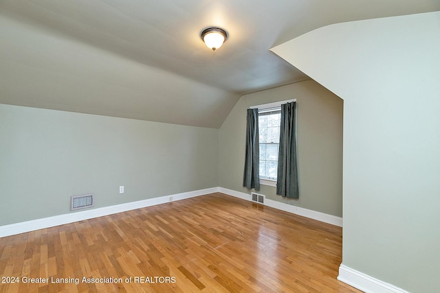 additional living space featuring lofted ceiling and light wood-type flooring