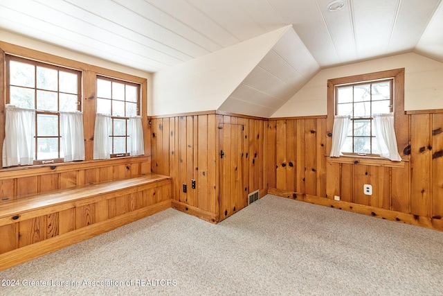 bonus room featuring light carpet, wood walls, and lofted ceiling