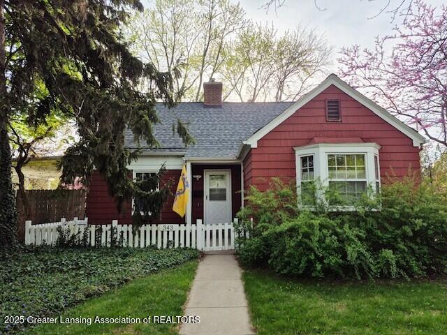 343 Highland Ave, East Lansing, MI 48823 - view of front facade featuring a chimney, a fenced front yard, and roof with shingles