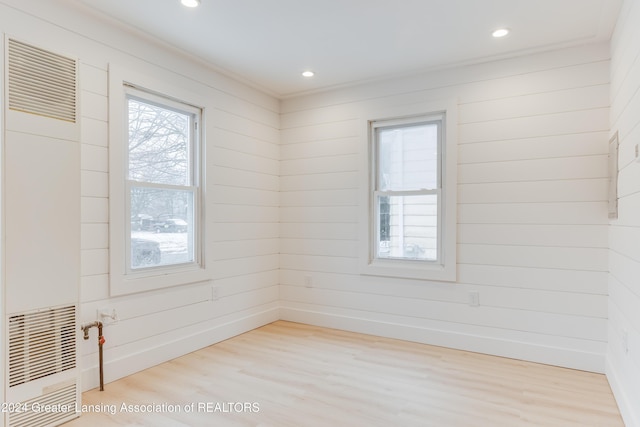 empty room featuring wood walls and light hardwood / wood-style flooring