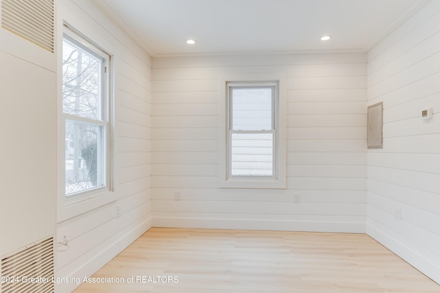 empty room featuring wood walls and light hardwood / wood-style floors