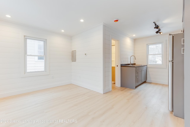 interior space featuring wooden walls, sink, rail lighting, and light hardwood / wood-style flooring