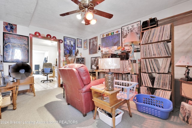 living room with a textured ceiling, ceiling fan, and carpet flooring