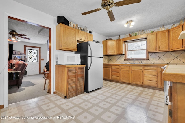 kitchen featuring sink, a textured ceiling, ceiling fan, tasteful backsplash, and stainless steel fridge