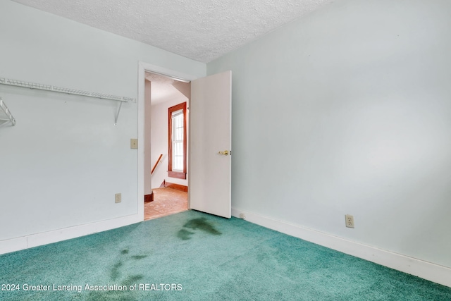 unfurnished bedroom with a textured ceiling and carpet flooring