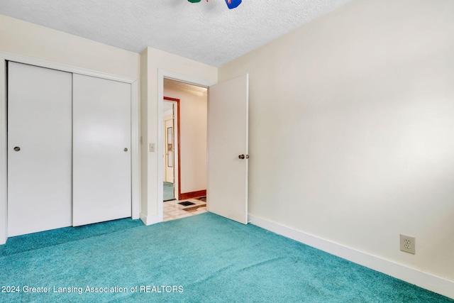 unfurnished bedroom featuring a textured ceiling, ceiling fan, a closet, and carpet