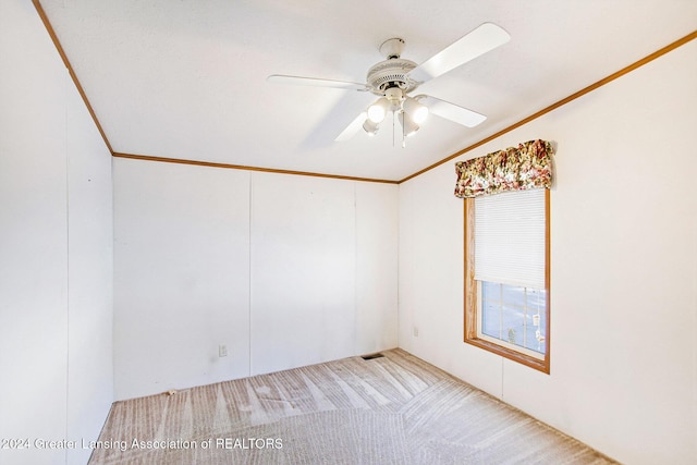 empty room featuring crown molding, vaulted ceiling, light colored carpet, and ceiling fan