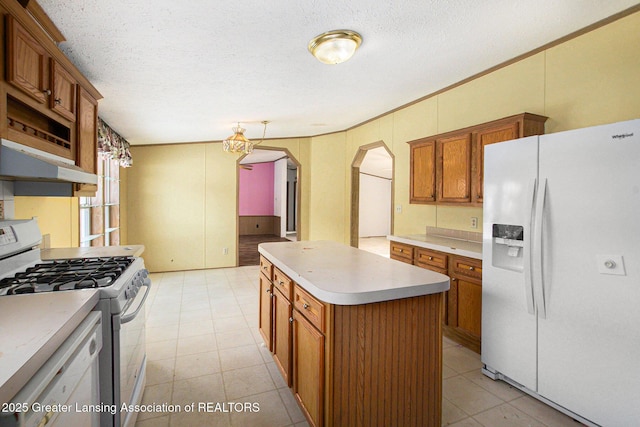 kitchen with a center island, a textured ceiling, and white appliances