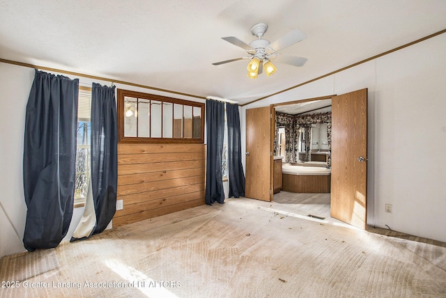 carpeted spare room featuring ceiling fan, ornamental molding, and wooden walls