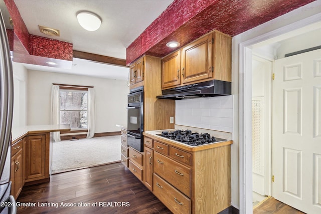 kitchen featuring dark wood-type flooring, backsplash, stainless steel gas cooktop, and oven