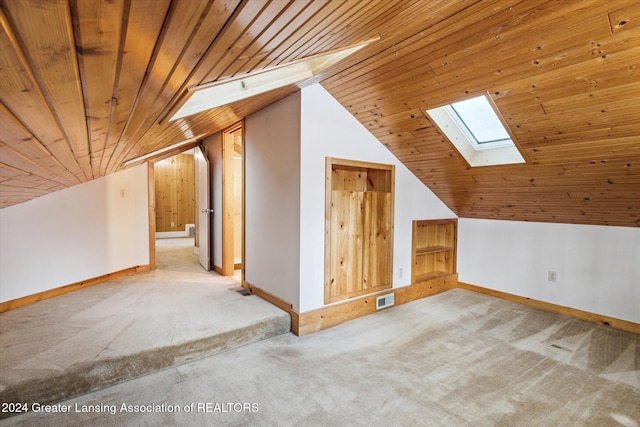 additional living space featuring light colored carpet, vaulted ceiling with skylight, and wood ceiling