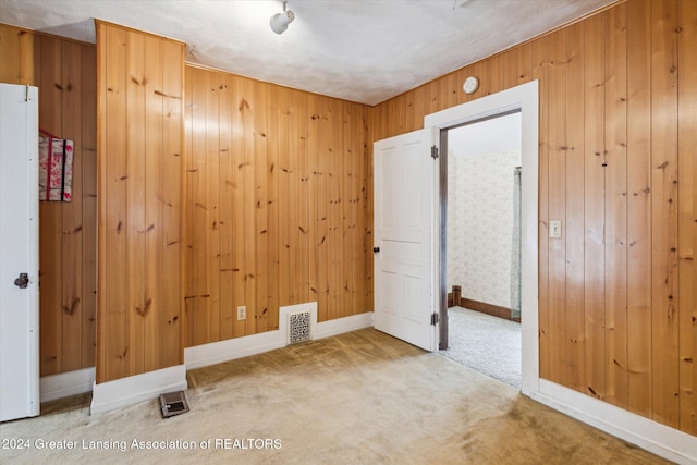 spare room with carpet flooring, wooden walls, and a textured ceiling