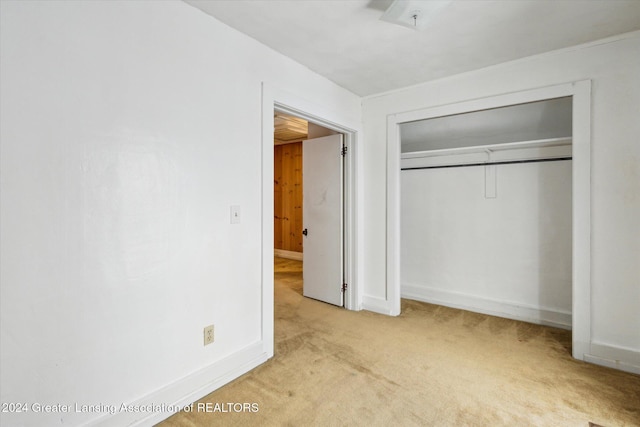 unfurnished bedroom with a closet and light carpet