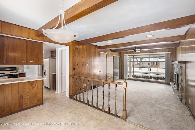 kitchen with range with gas cooktop, light countertops, wood walls, refrigerator with ice dispenser, and pendant lighting