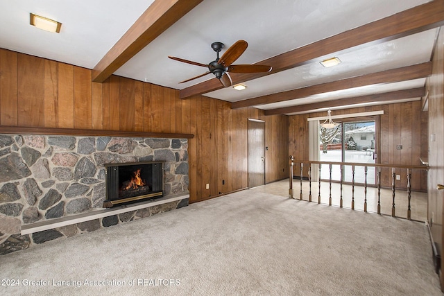 unfurnished living room with a fireplace, carpet flooring, beam ceiling, and wooden walls