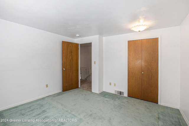 unfurnished bedroom featuring light carpet, a closet, visible vents, and baseboards