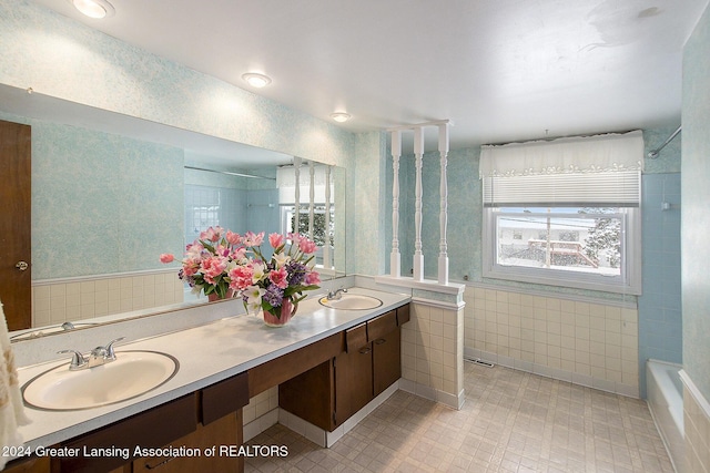 full bath featuring double vanity, wallpapered walls, and a sink