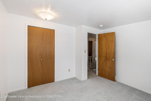 unfurnished bedroom with a closet and light colored carpet