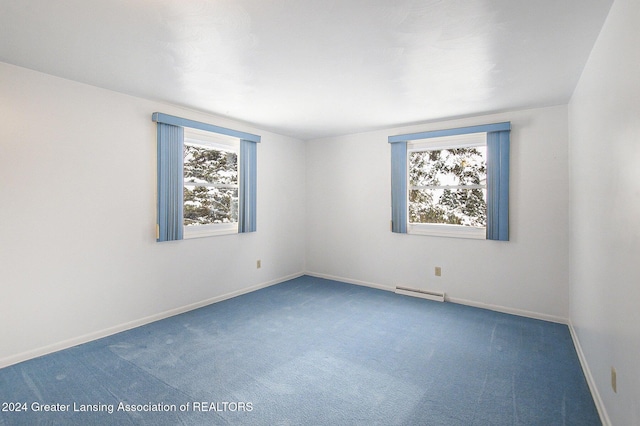 empty room with carpet, a baseboard heating unit, and baseboards