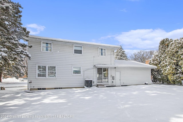 snow covered back of property with entry steps, central AC unit, and a chimney