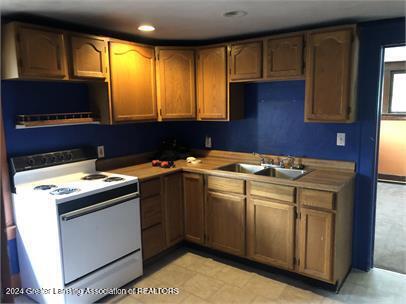 kitchen with sink, light tile patterned floors, and white electric range oven