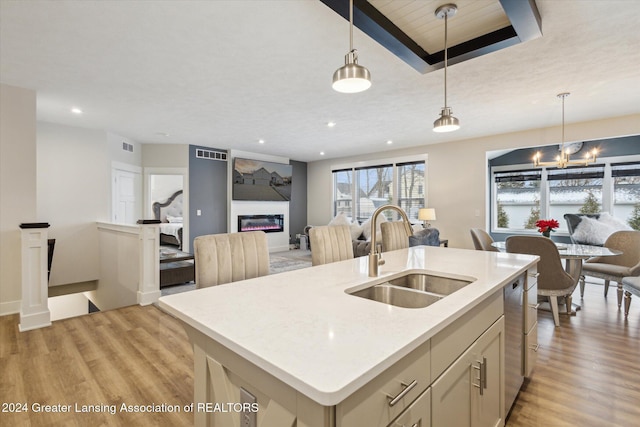 kitchen featuring dishwasher, decorative light fixtures, an island with sink, and sink