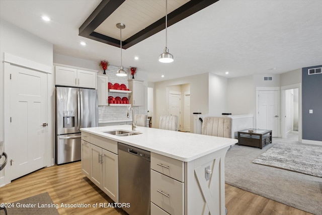 kitchen with appliances with stainless steel finishes, a kitchen island with sink, sink, decorative light fixtures, and white cabinets