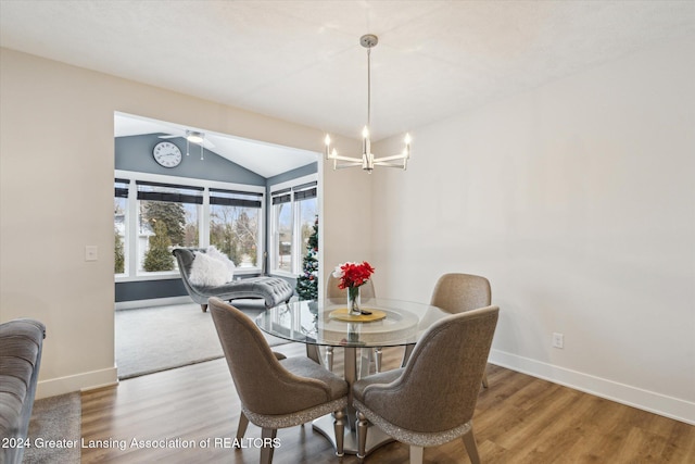 dining area with hardwood / wood-style floors, ceiling fan with notable chandelier, and vaulted ceiling