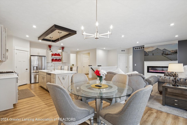 dining room featuring light hardwood / wood-style floors, sink, and a chandelier