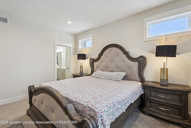 bedroom with light colored carpet and connected bathroom