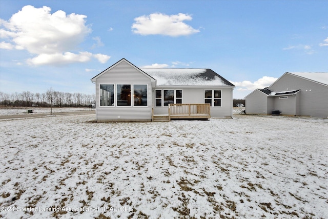 snow covered back of property featuring a wooden deck