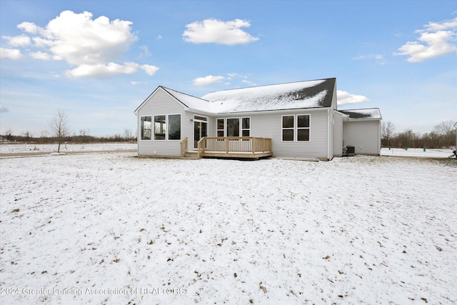 snow covered rear of property featuring a sunroom and a wooden deck