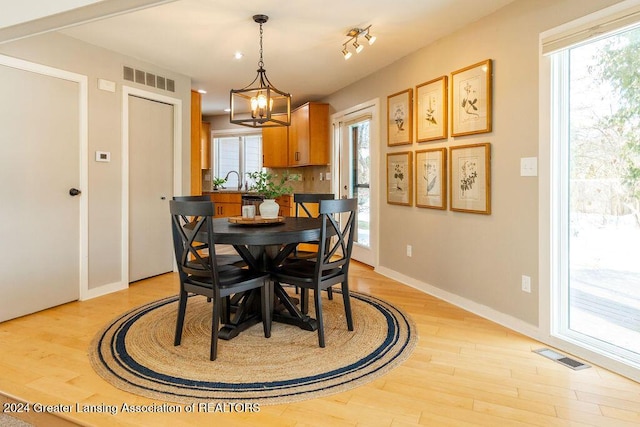 dining space featuring sink, an inviting chandelier, and light hardwood / wood-style flooring