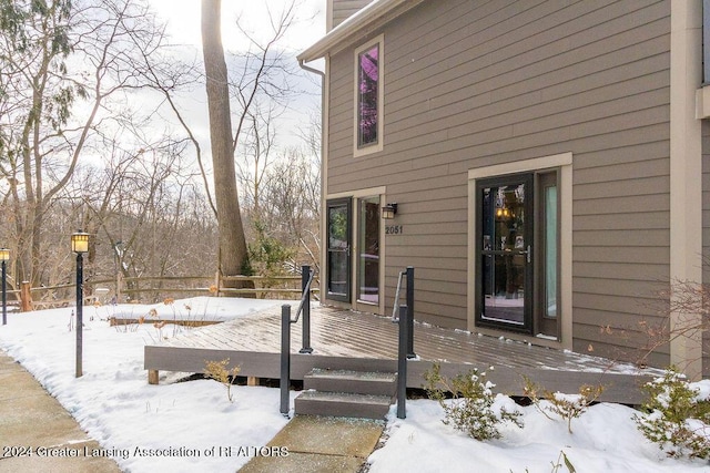 snow covered property entrance with a wooden deck