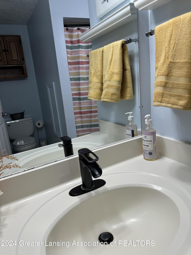 bathroom featuring sink, a textured ceiling, and toilet