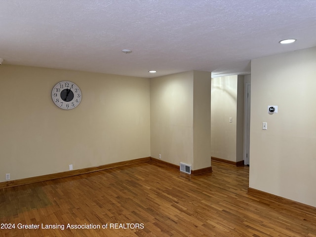 spare room featuring a textured ceiling and hardwood / wood-style flooring