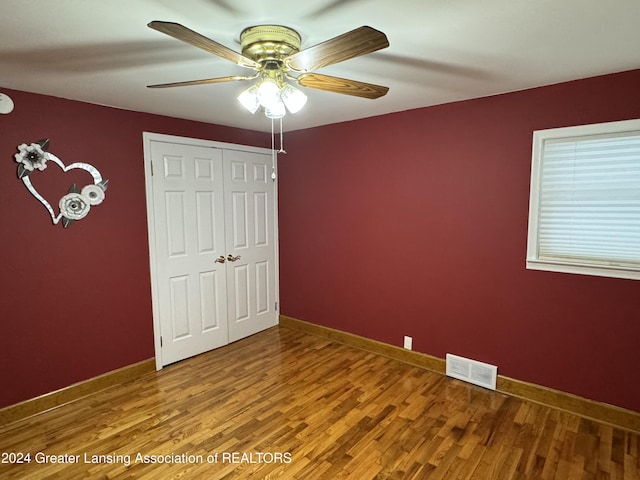 unfurnished bedroom with ceiling fan, a closet, and hardwood / wood-style flooring