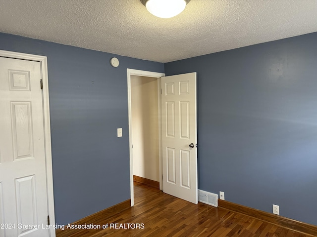 spare room with a textured ceiling and dark hardwood / wood-style flooring